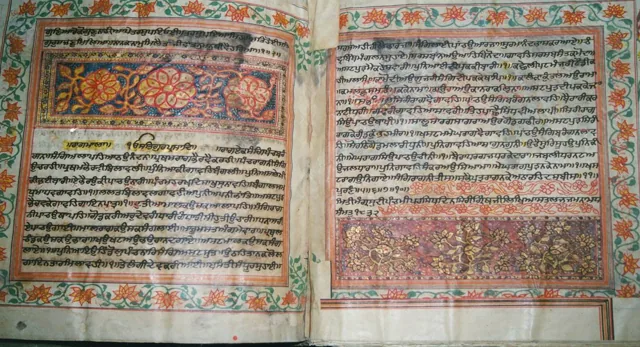 An illuminated handwritten Saroop open at Raagmala, with painted floral borders and the closing figures.